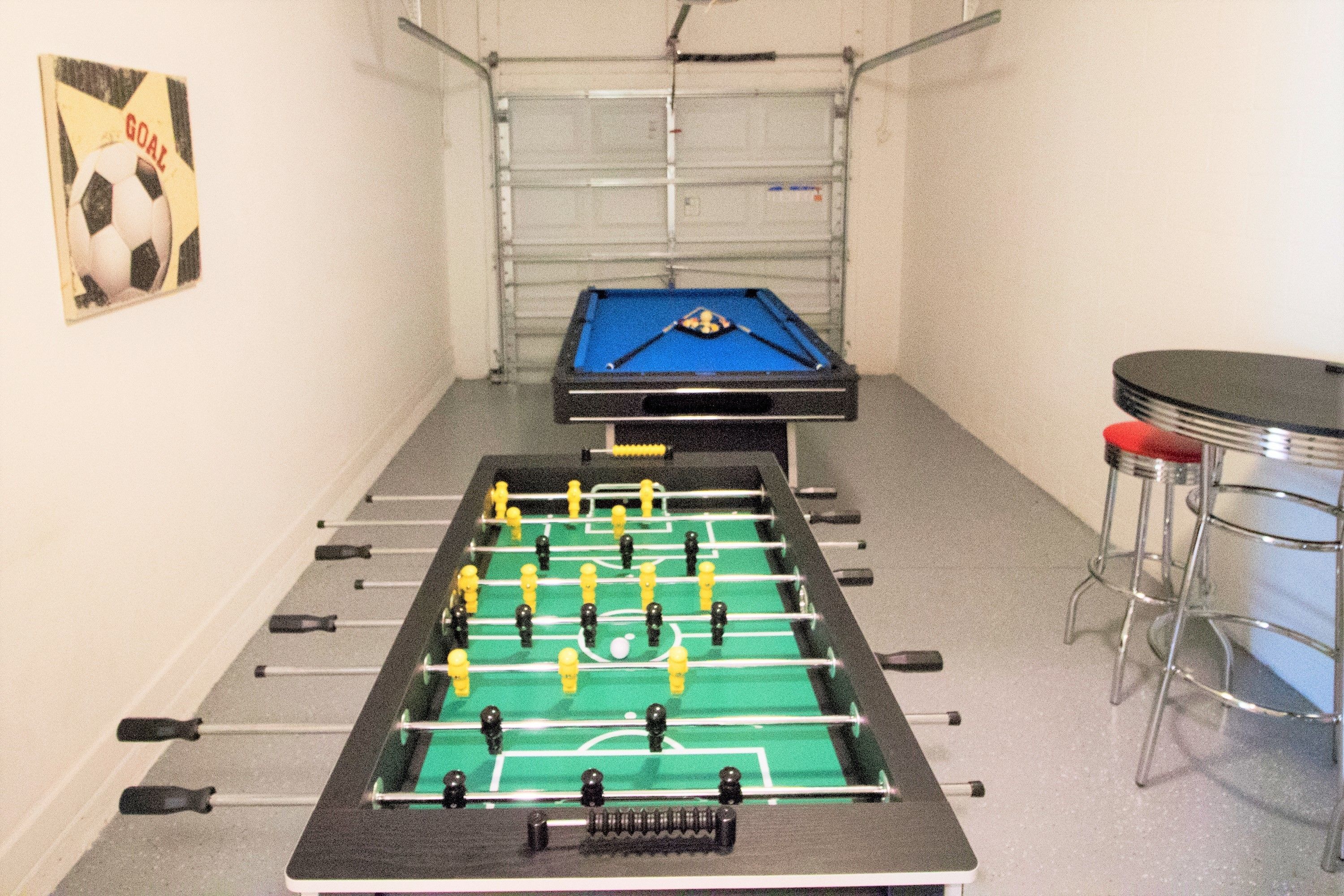 A foosball table in a room with a metal gate and a bar stool.