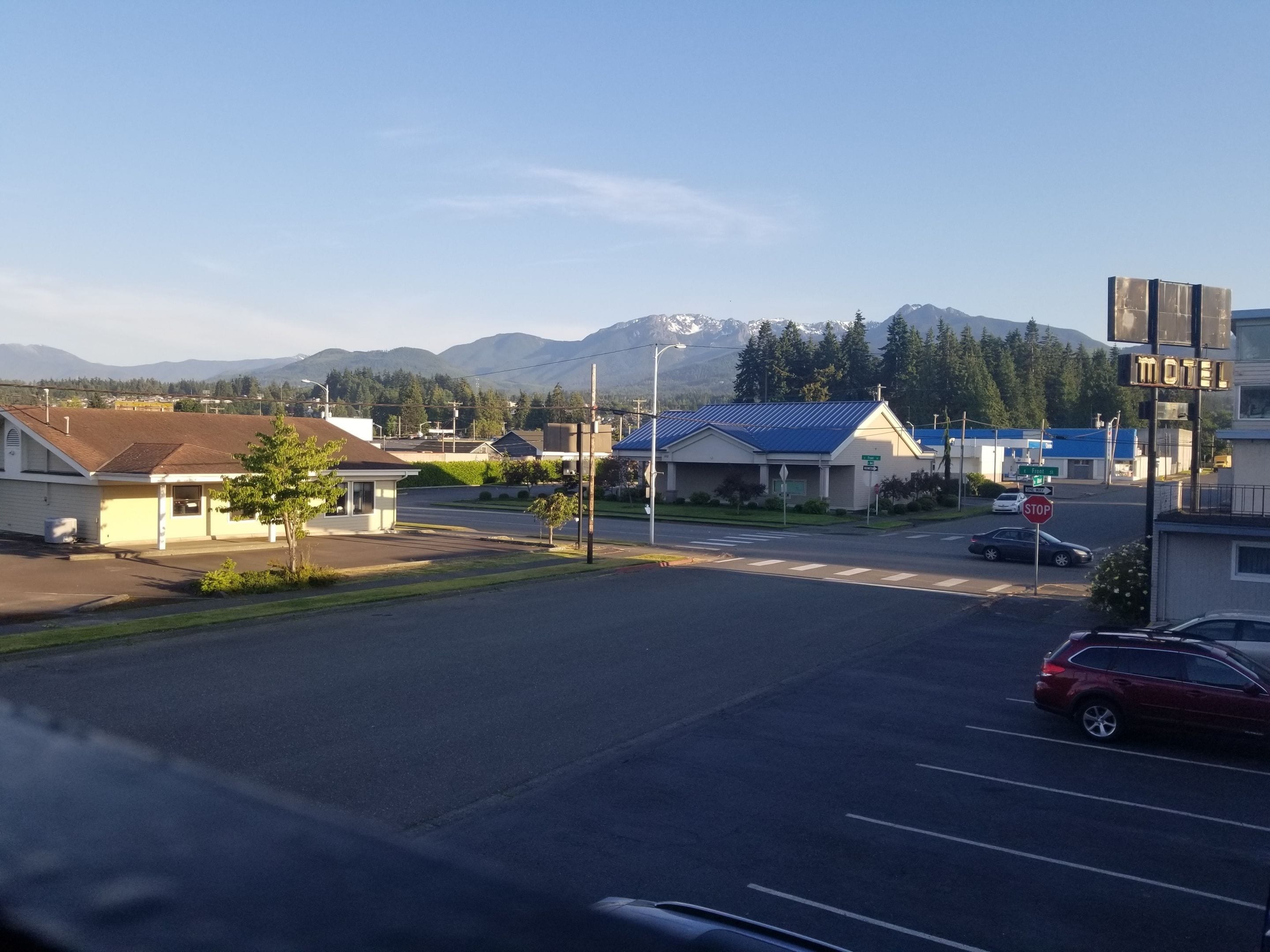 A motel with a blue roof, a stop sign, and a mountain in the background.