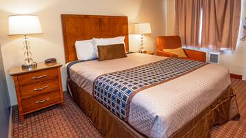 A hotel room with a large bed, two bedside tables, a chair, and a window with curtains.