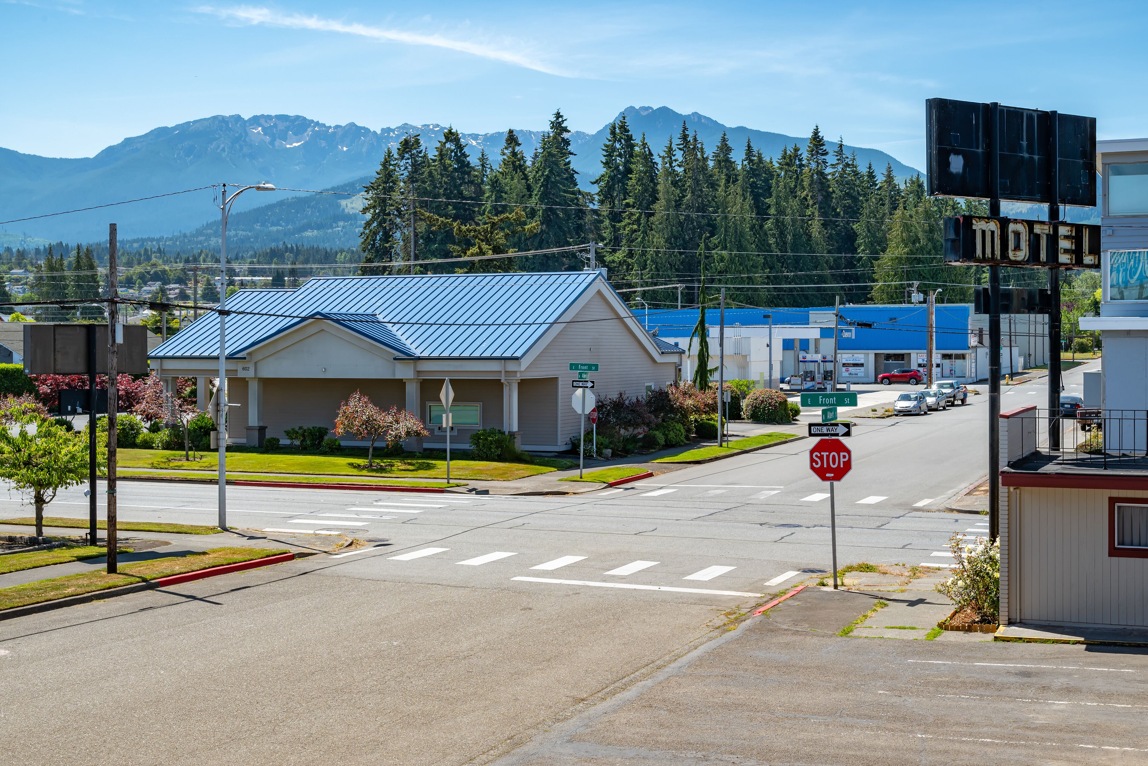 A motel with a blue roof, a stop sign, and a mountain backdrop.