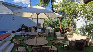 A patio area with a pool, outdoor furniture, and a hammock. - Real Hotel (Sete Lagoas)