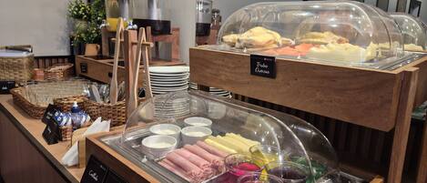 A buffet area with various food options, including meats, cheeses, and beverages, displayed in clear containers.