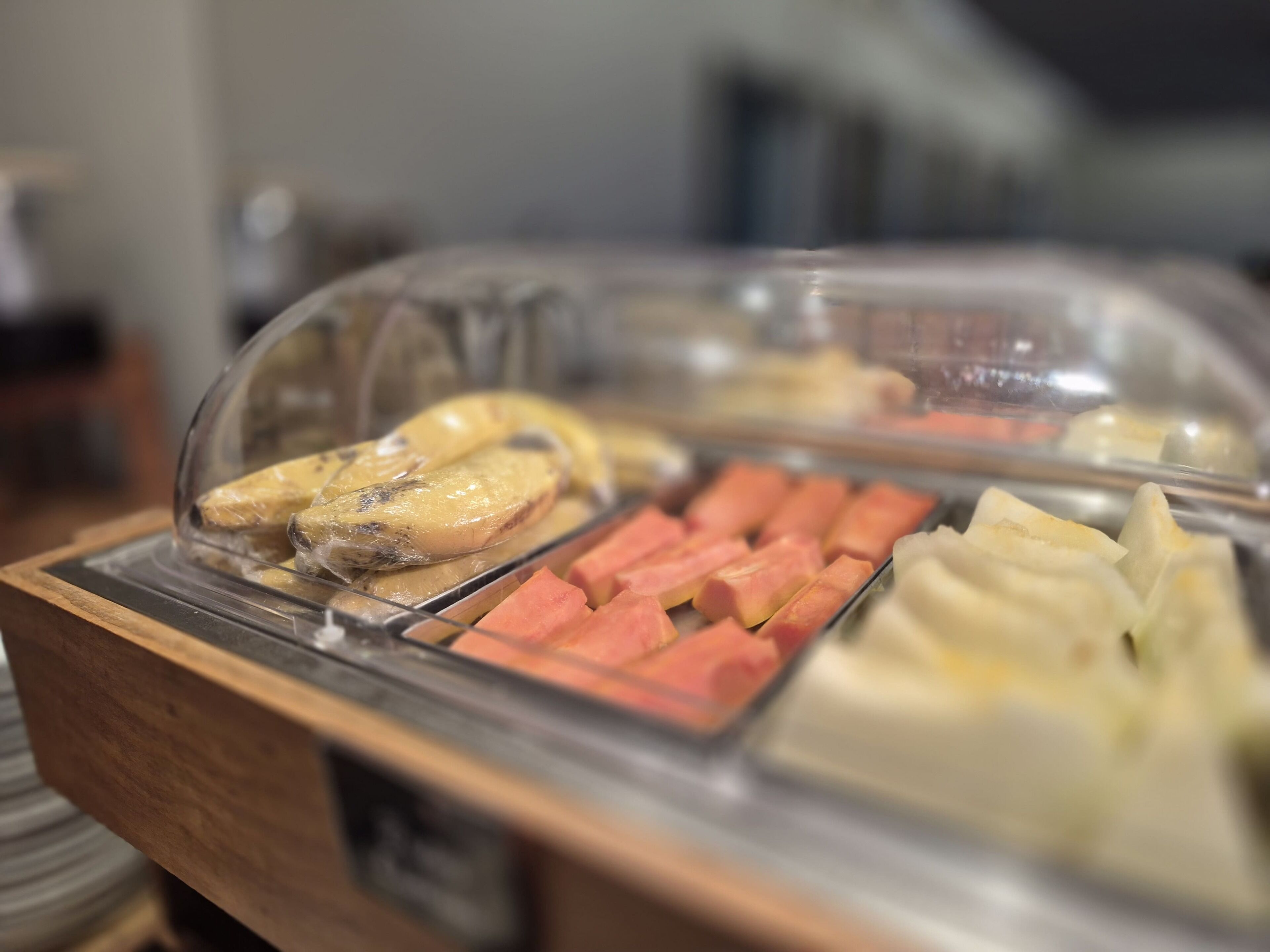 Un bufé con diversas opciones de comida, entre ellas plátanos, zanahorias y albóndigas.
