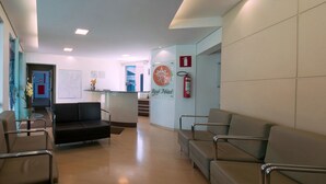 A hotel reception area with a reception desk, a fire extinguisher, and a sign that reads "Real Hotel." - Real Hotel (Sete Lagoas)