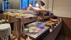 A buffet setup with various food items and utensils. - Real Hotel (Sete Lagoas)