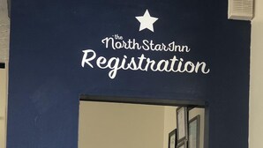A registration desk with a dark blue wall and a sign above it that reads "The NorthStar Inn Registration". - The North Star Inn (Corinth)