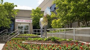 A visitor center with a statue of a horse, surrounded by a landscaped garden with red flowers. - The North Star Inn (Corinth)