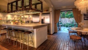 A modern kitchen with a central island, bar stools, and a dining area with a chandelier. - Villas Enrique (Puerto Vallarta)