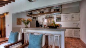 A kitchen with a central island, white cabinets, and a tiled floor. - Villas Enrique (Puerto Vallarta)