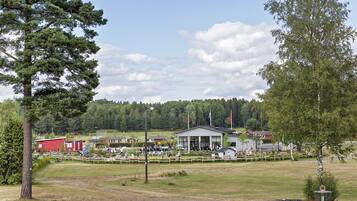 A rural setting with a building that appears to be a community center or clubhouse, surrounded by a fenced area with people gathered.