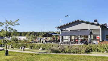 En restaurang med uteservering, en klar himmel och ett flygplan i fjärran.
