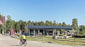 A building with a covered outdoor area, a bicycle path, and a fenced grassy area.