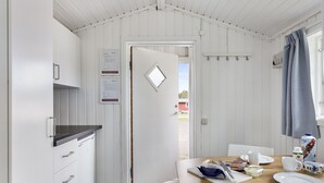 A dining area with a wooden table, white chairs, and a breakfast setting including a jug of milk, a bowl of cereal, and a coffee cup. - First Camp Karlstad (Karlstad)