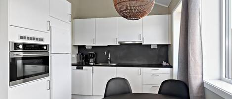 A modern kitchen with white cabinets, a black countertop, and a dining table with chairs.