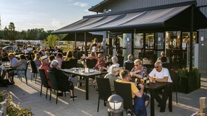 An outdoor patio area with tables and chairs, surrounded by a building with a covered walkway. - First Camp Karlstad (Karlstad)