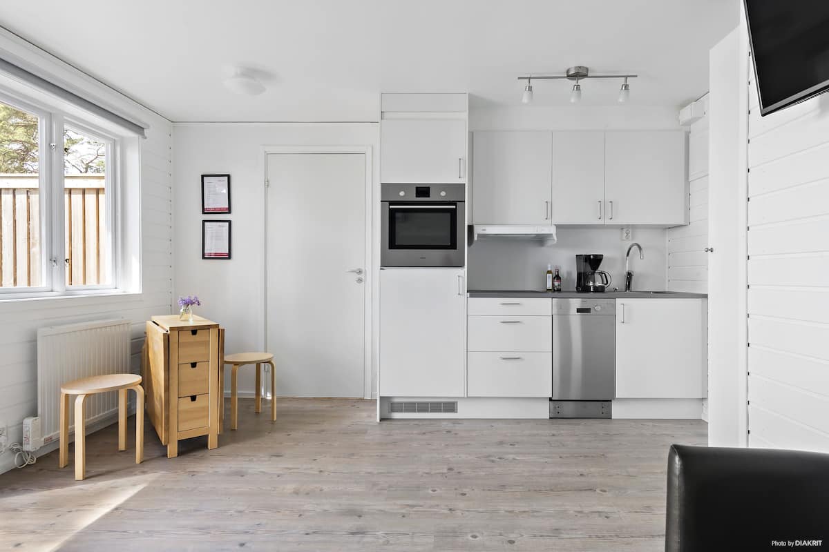 Een moderne keuken met witte kasten, roestvrijstalen apparatuur en een eethoek met houten meubels.