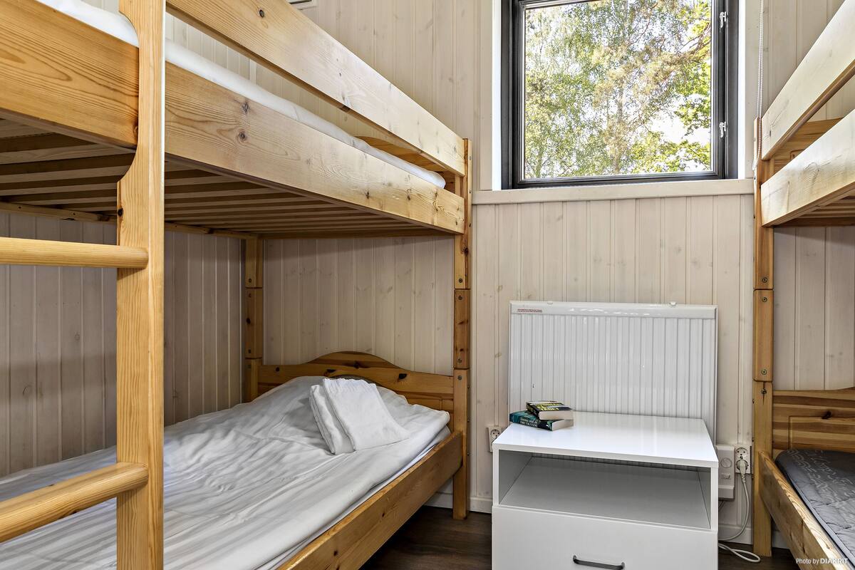 Een slaapkamer met een stapelbed, een raam, een wit bureau en een radiator.