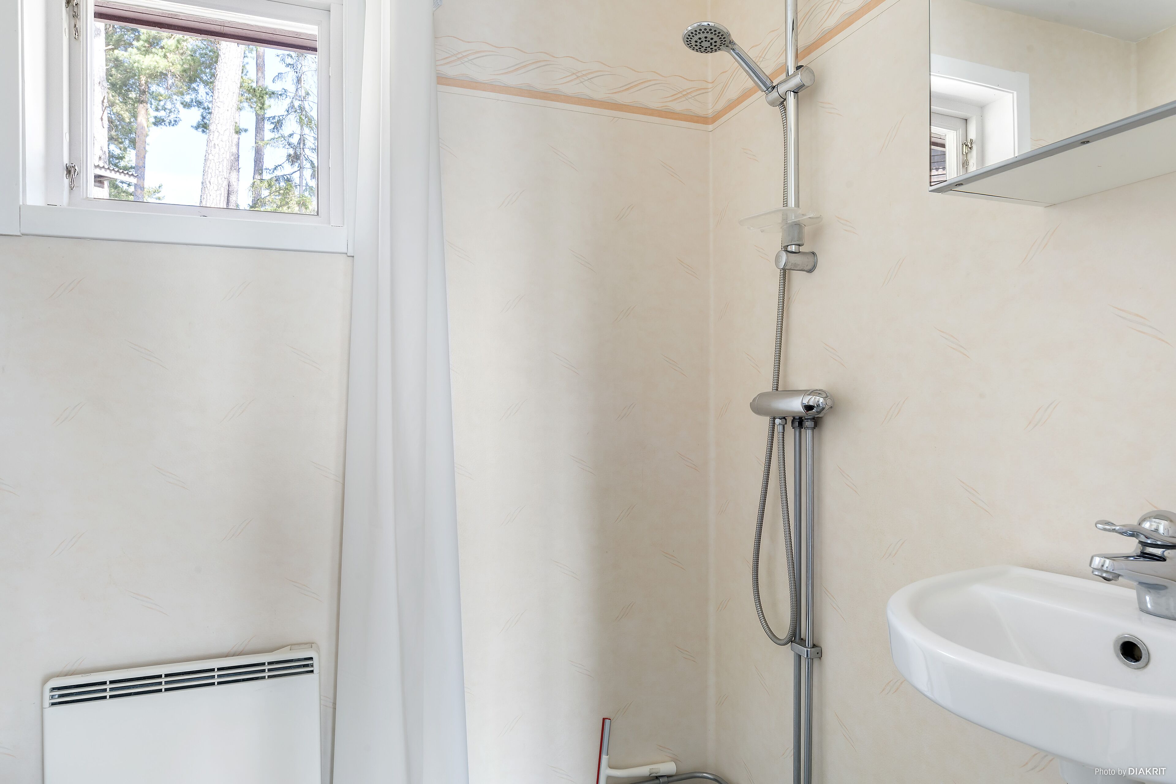 Une salle de bain avec une douche, un lavabo et une fenêtre.