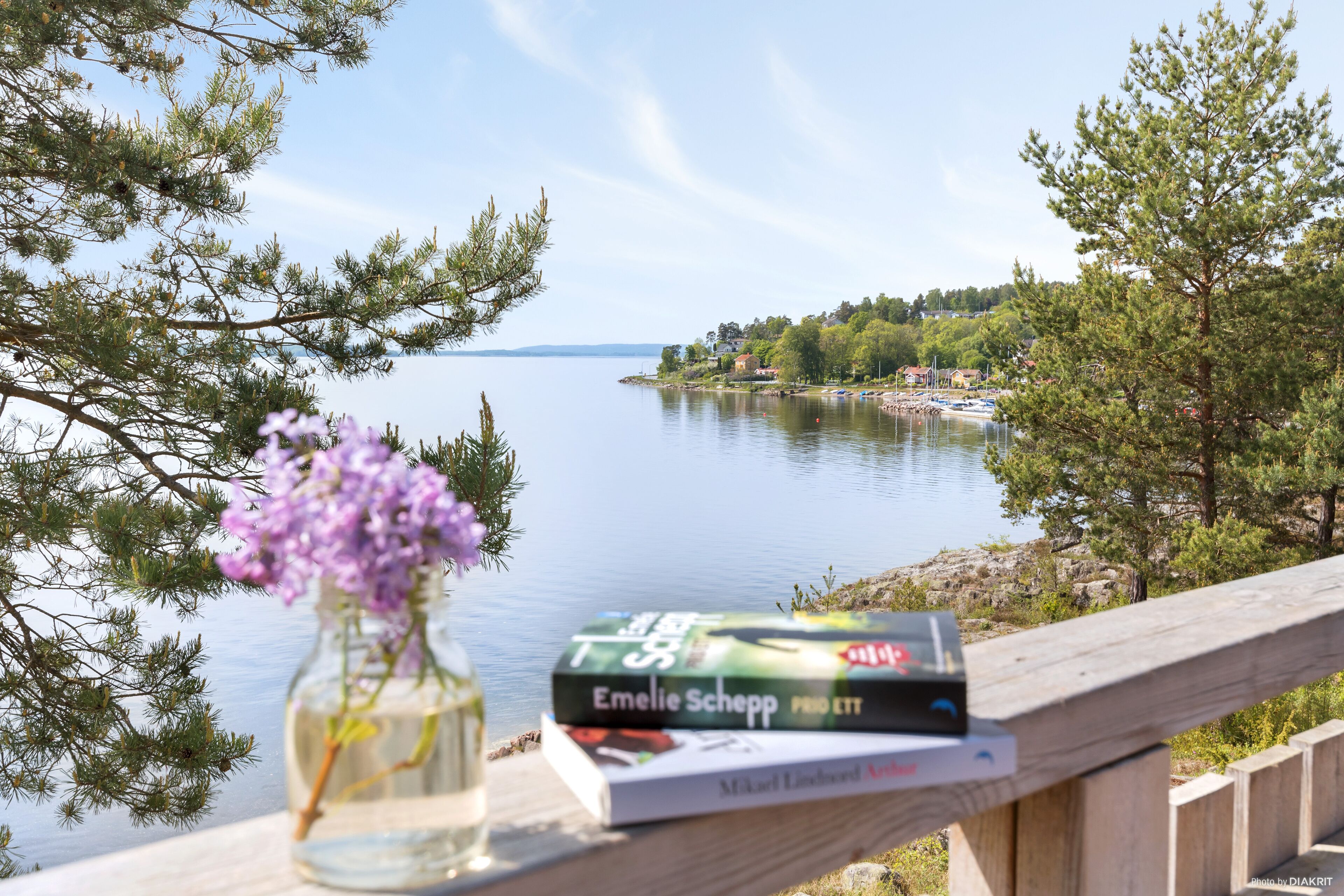 A wooden deck with a book and a vase of flowers.