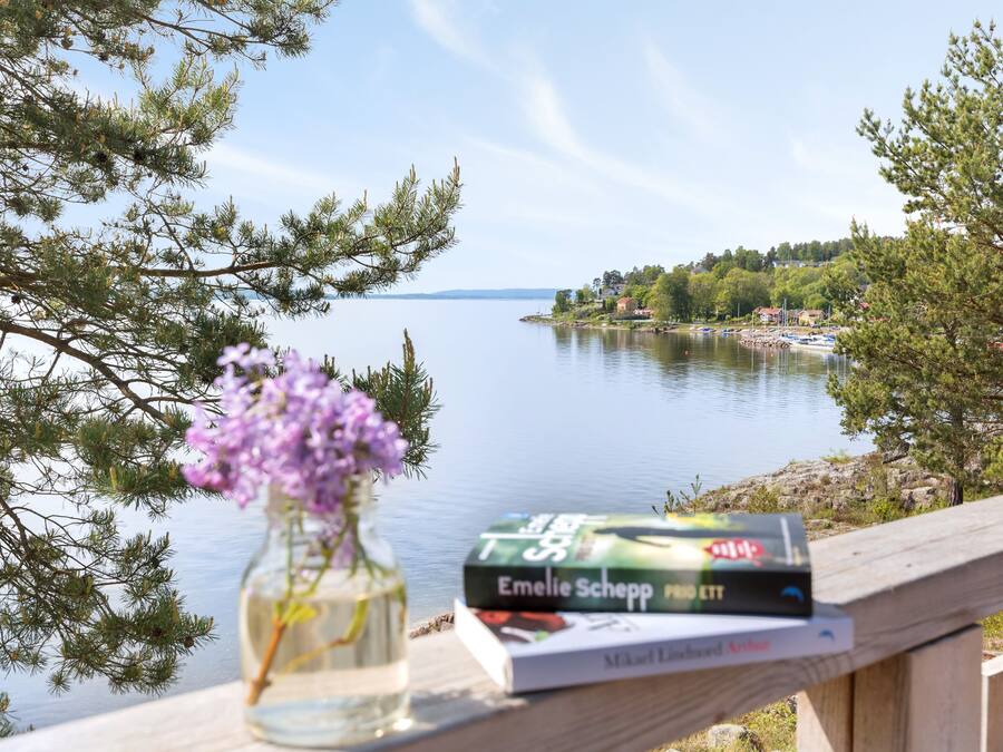 Eine Holzterrasse mit einem Buch und einer Blumenvase.