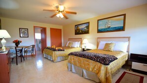 A hotel room with two beds, a desk, a chair, a ceiling fan, and artwork on the walls. - Chesters Bonefish Lodge (Chesters)