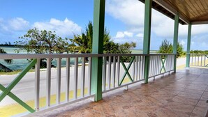 A covered outdoor area with a view of the sea, featuring a tiled floor and green and white railings. - Chesters Bonefish Lodge (Chesters)