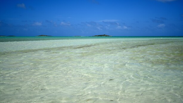 A clear view of a beach with turquoise water and distant islands. - Chesters Bonefish Lodge (Chesters)