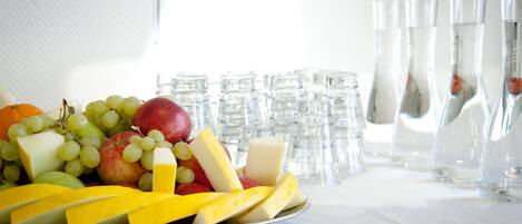 A fruit platter on a table with glasses and water bottles in the background.