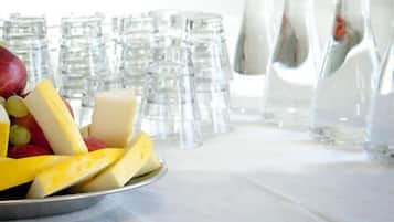 Ett bord med ett fat med frukt och ost, omgivet av genomskinliga glasflaskor och glas.