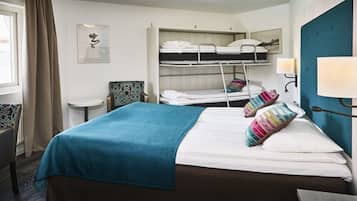 Een hotelkamer met een eenpersoonsbed, een stapelbed, een klein tafeltje en een stoel.