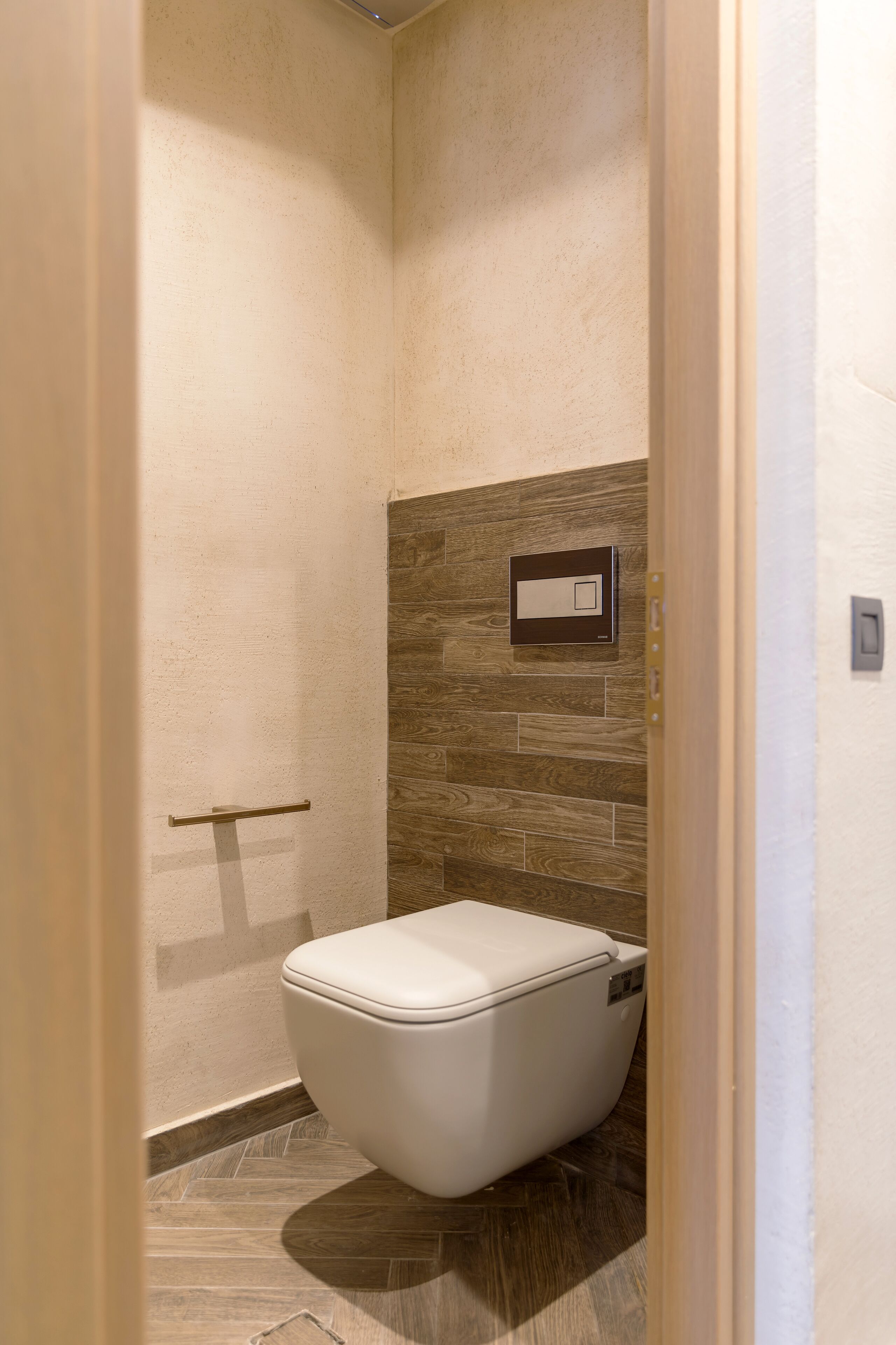 Un baño pequeño y funcional con inodoro, perchero y aplique de pared.