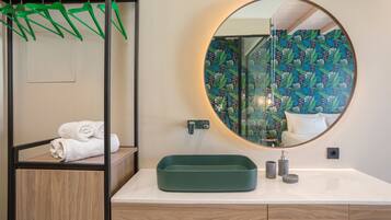 Een badkamer met een houten wastafelmeubel, een ronde spiegel en een groene wastafel.