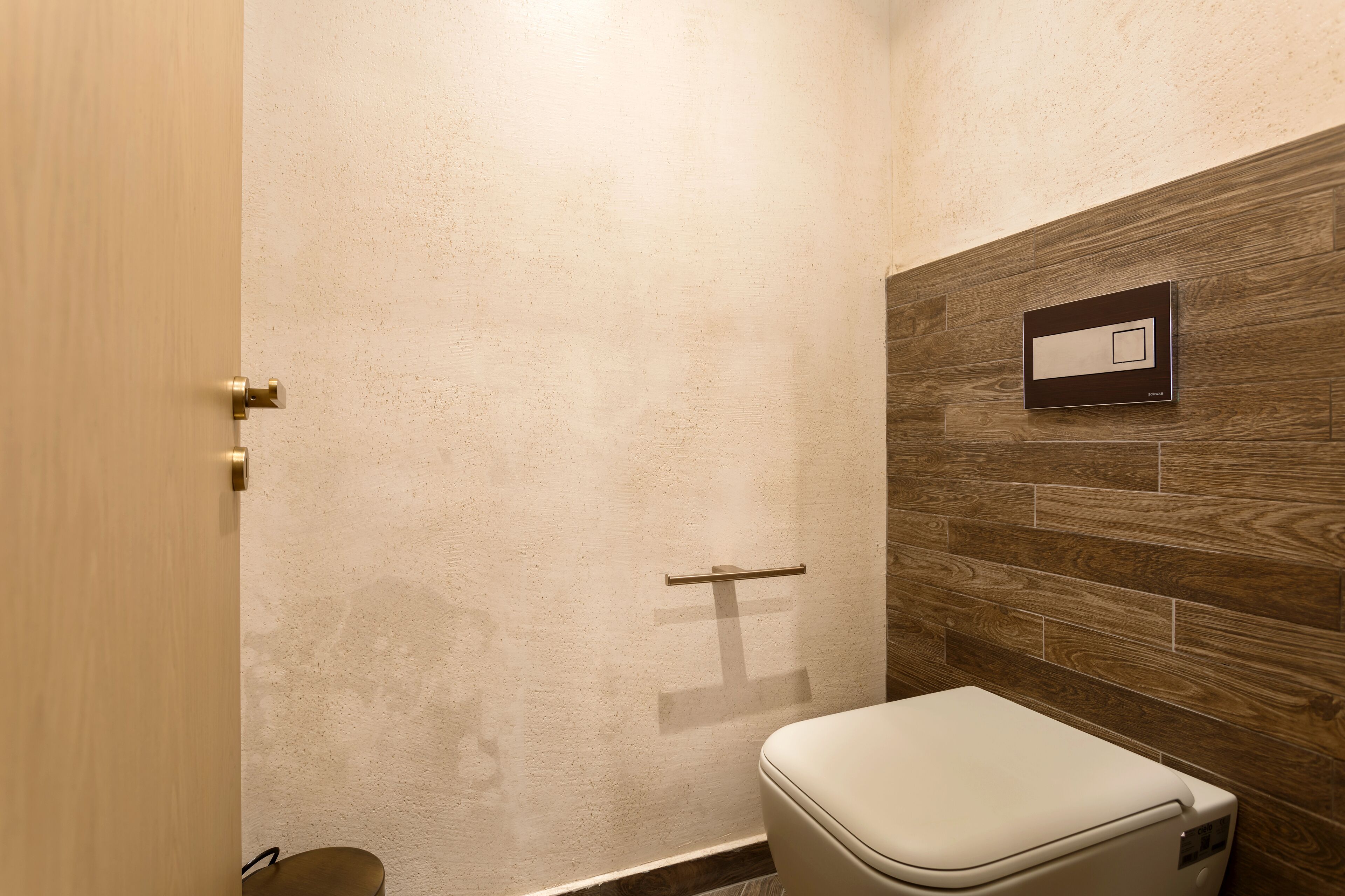 Un baño con pared de madera, un inodoro y un perchero para toallas.