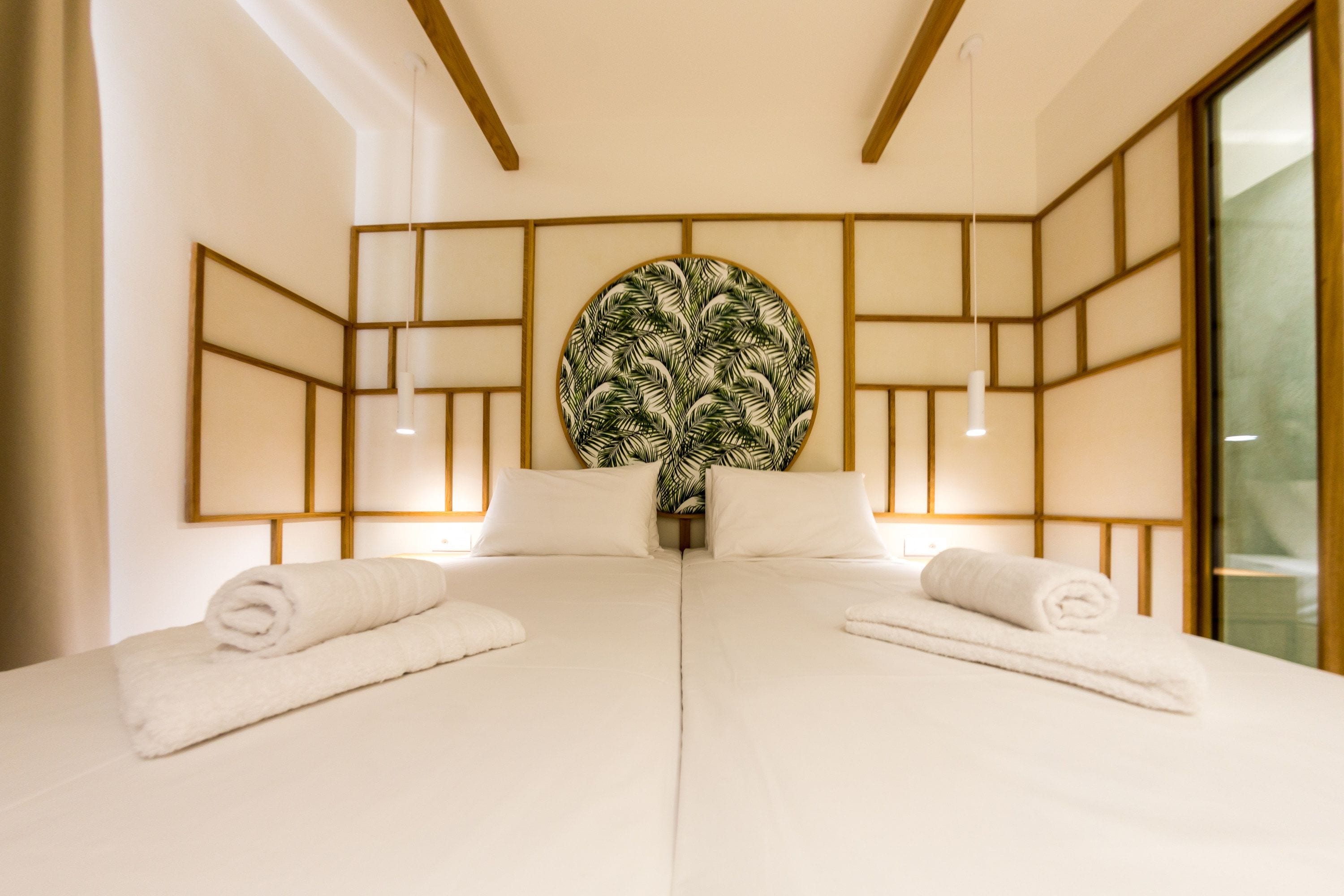 A hotel room with a large bed, two bedside tables, a wall-mounted artwork, and a window.