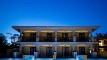 Un edificio de varios pisos con balcones, arcos y una piscina.