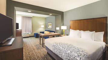 Ein Hotelzimmer mit einem großen Bett, einem Schreibtisch, einem Sessel und einem Fernseher.