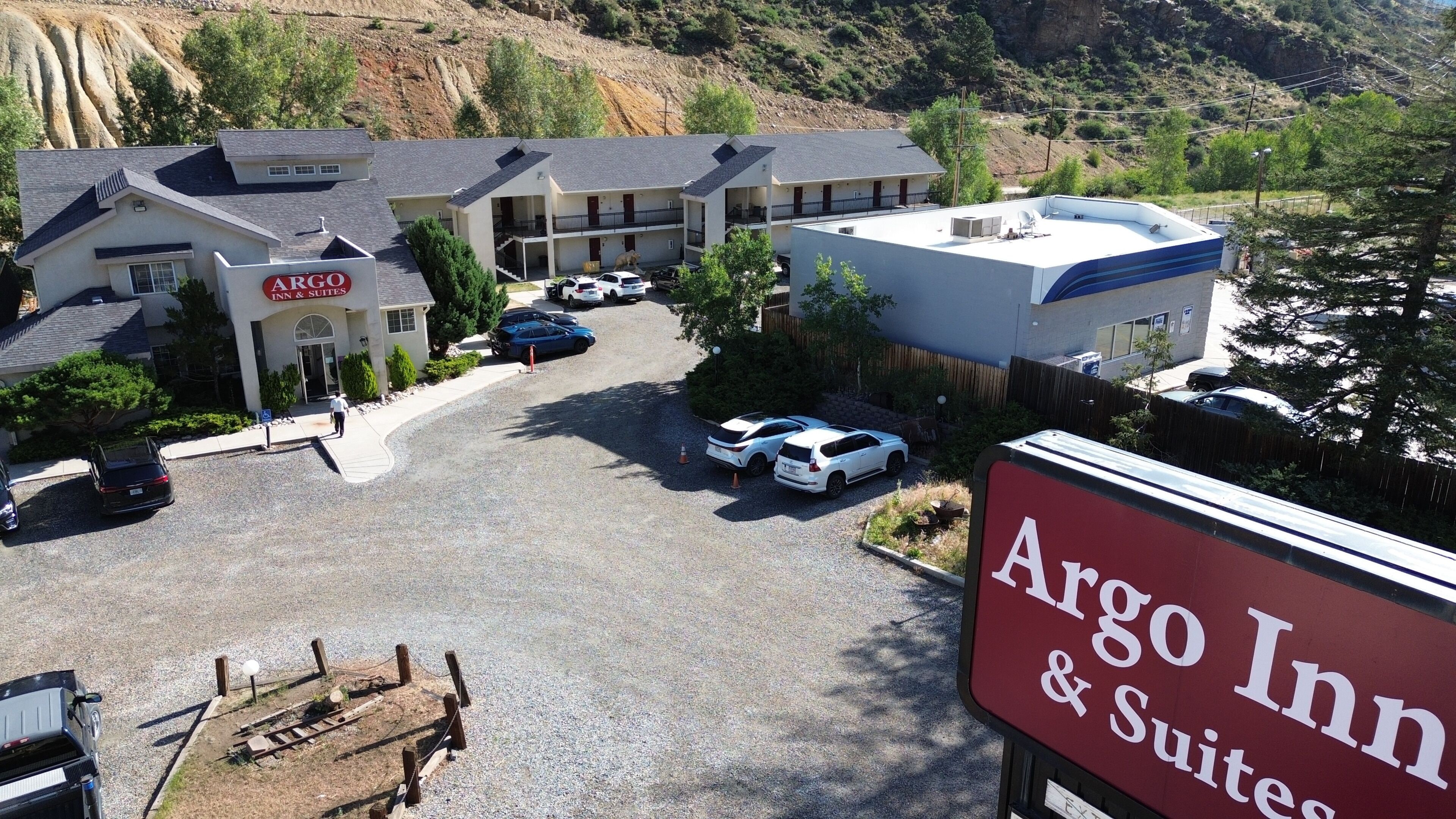 An Argo Inn & Suites with a parking lot, multiple buildings, and a mountainous backdrop.