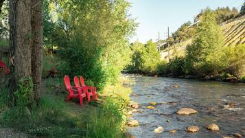 Une rivière avec des rochers, un arbre et des chaises rouges au bord de l’eau.