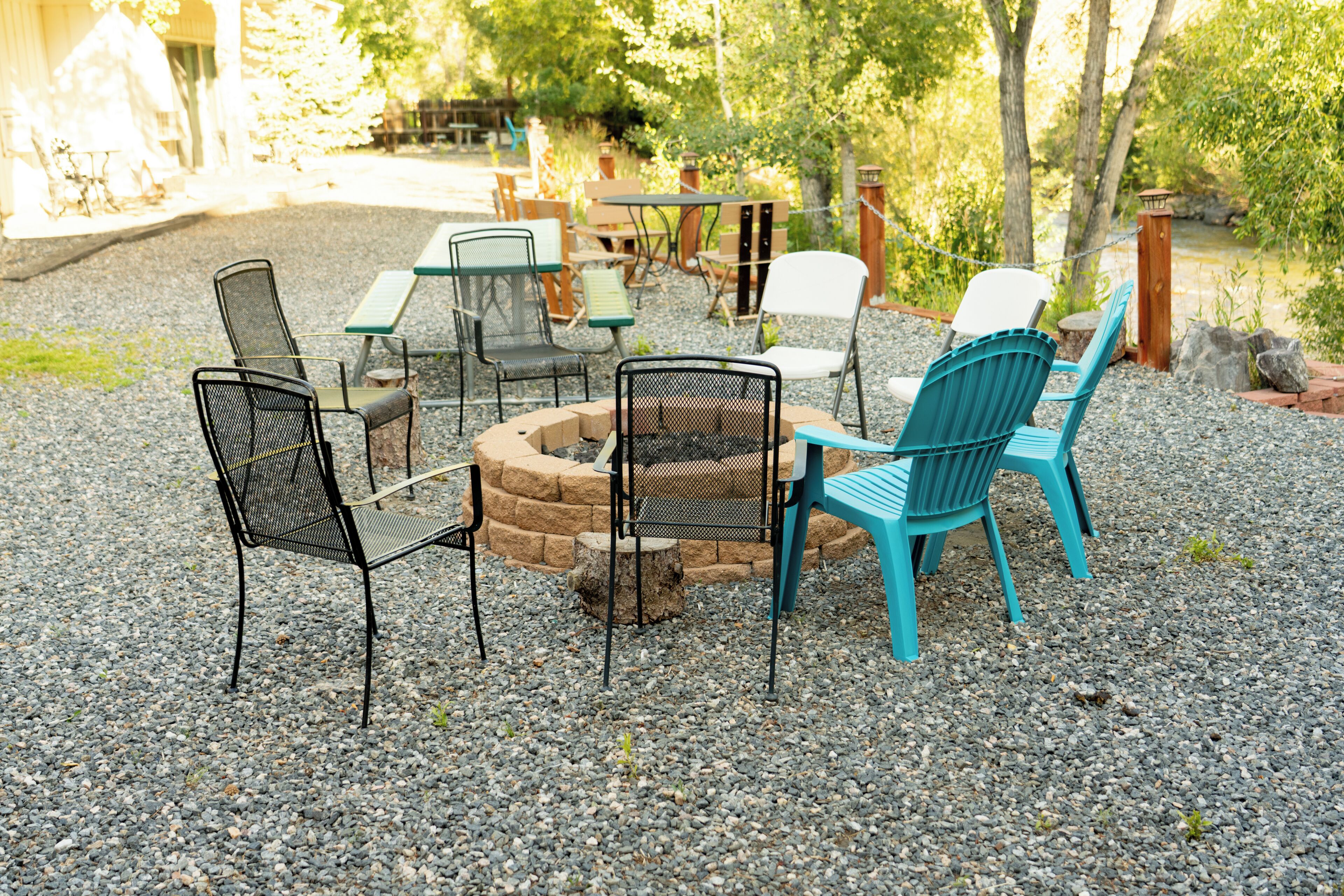 An outdoor seating area with a fire pit, chairs, and tables.