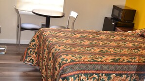 A hotel room with a bed, a chair, a small table, and a microwave. - Hotel Sunrise (San Francisco)