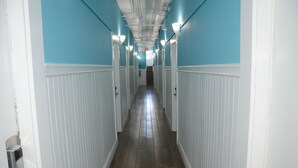 A long, narrow hallway with white wainscoting and blue walls, leading to a staircase at the end. - Hotel Sunrise (San Francisco)