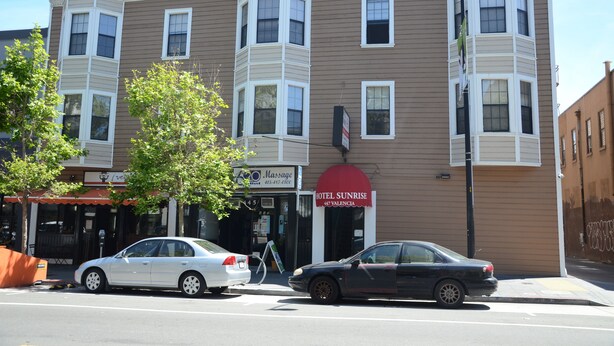 A multi-story building with a corner entrance, a massage parlor, and a hotel named 'Hotel Sunrise' with a red awning. - Hotel Sunrise (San Francisco)