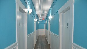 A hallway with blue walls and white trim, featuring doors with numbers and a tiled floor. - Hotel Sunrise (San Francisco)