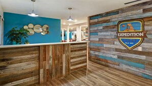 Un espace d’accueil avec un comptoir en bois, des murs bleus et le logo de « Expedition Lodge Mod. Utah ».