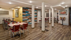 Un espace repas moderne avec un plancher en bois, des chaises rouges et un panneau indiquant les toilettes.