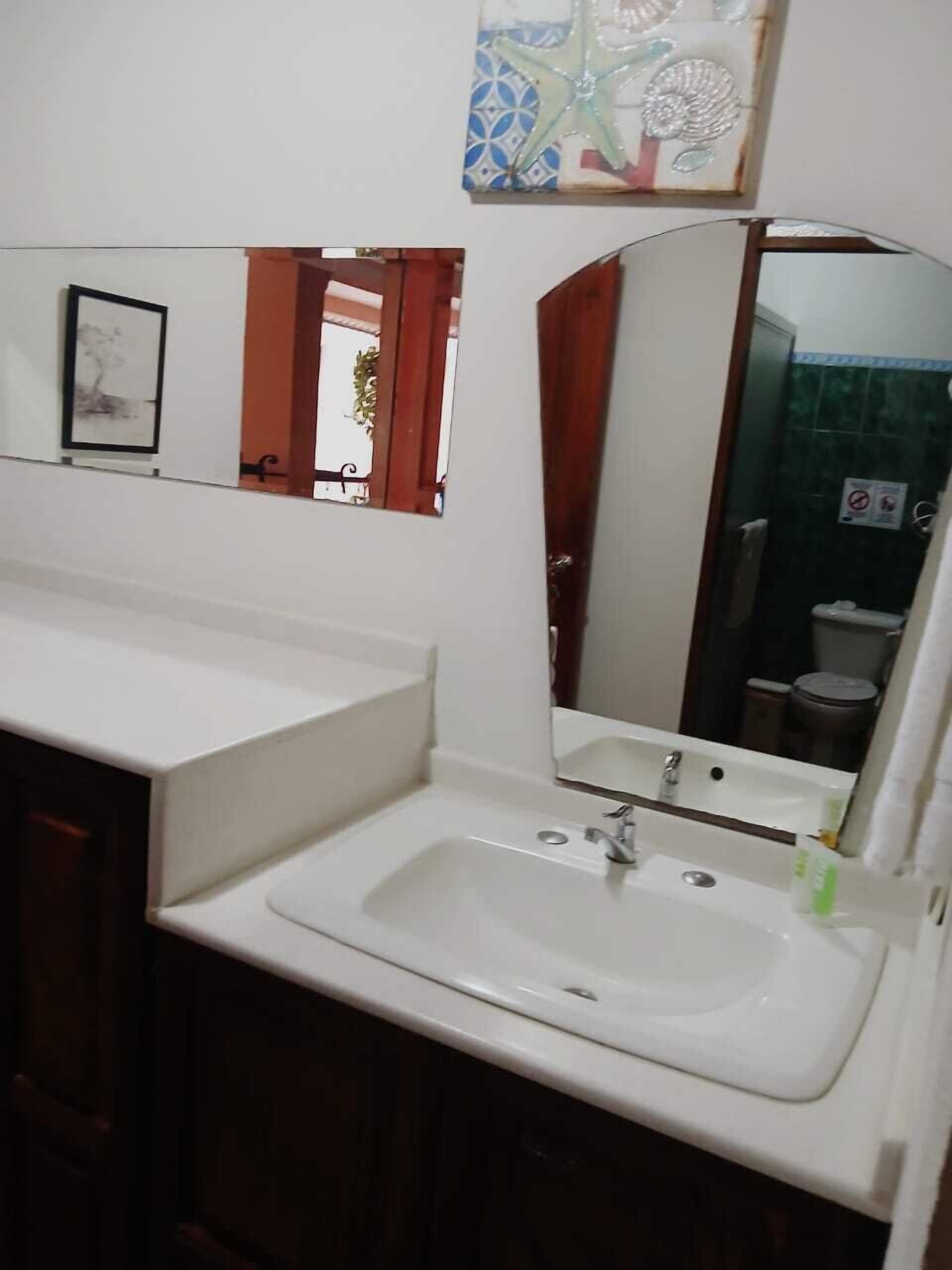 Un bagno con un lavandino bianco, uno specchio e un quadro incorniciato appeso al muro.