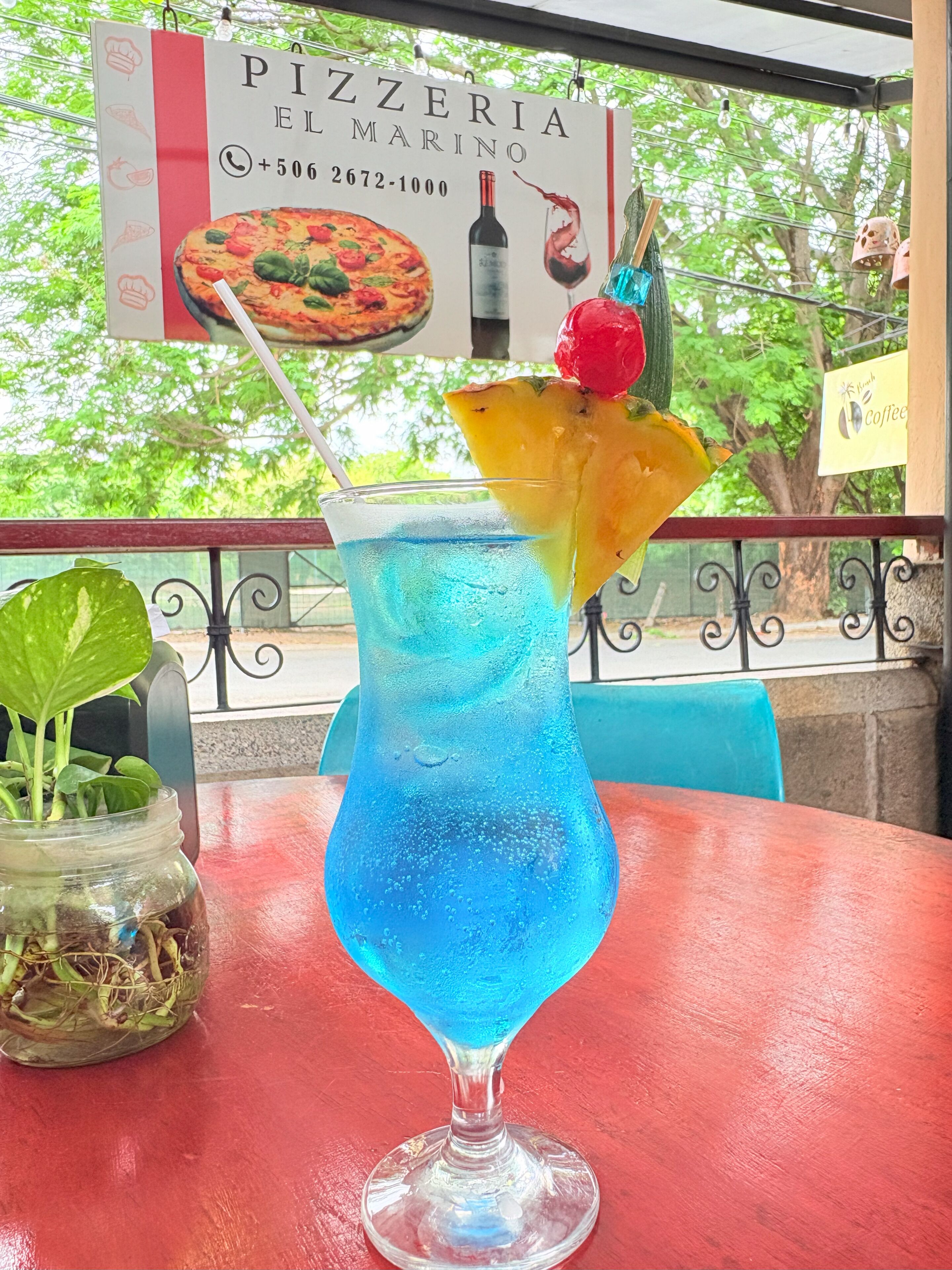Ein Pizzeriaschild mit einer Pizza, einer Weinflasche und einem Cocktailglas mit Fruchtbeilage.