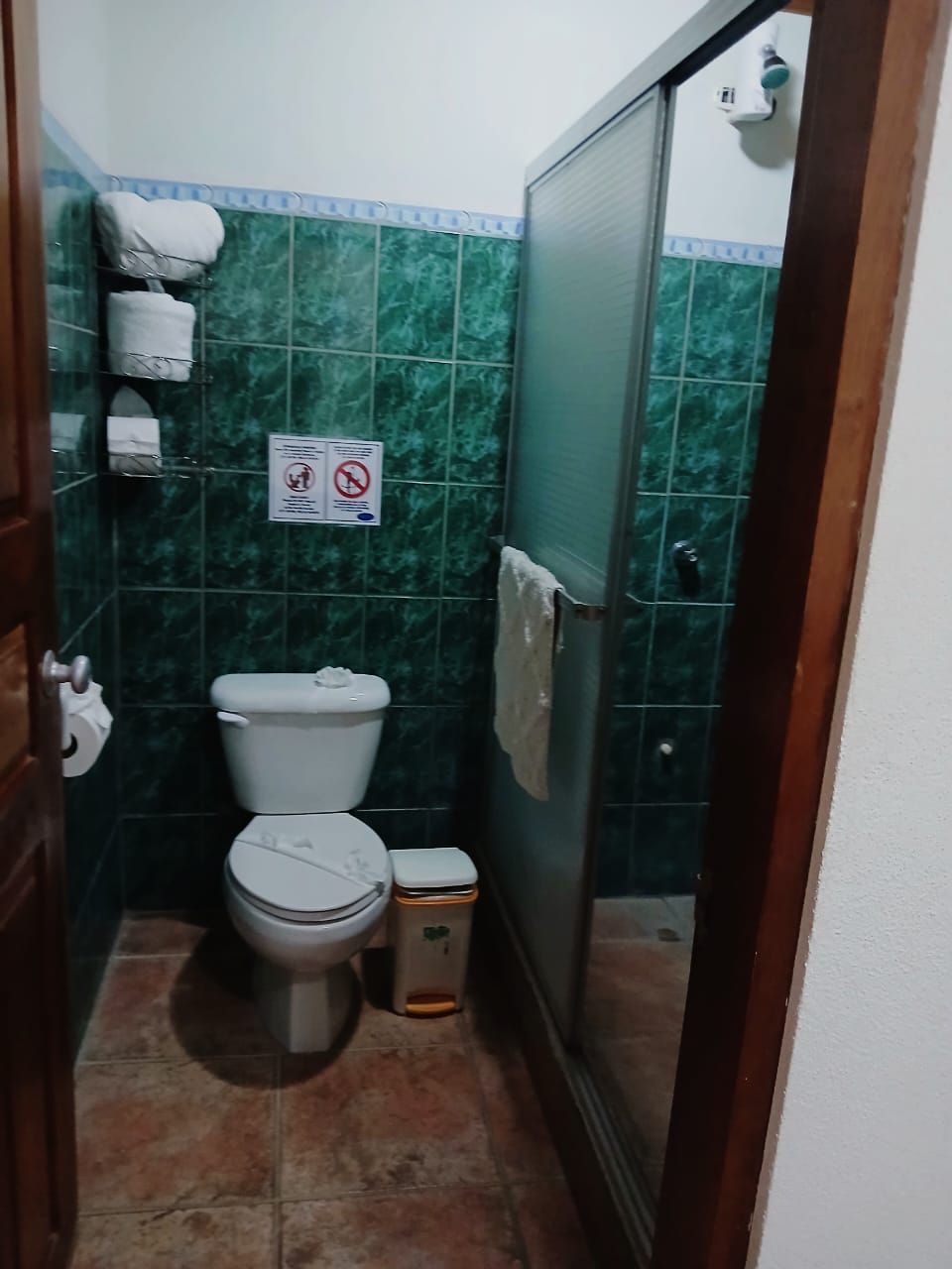 Un baño pequeño con inodoro, un cubo de basura y zona de ducha.