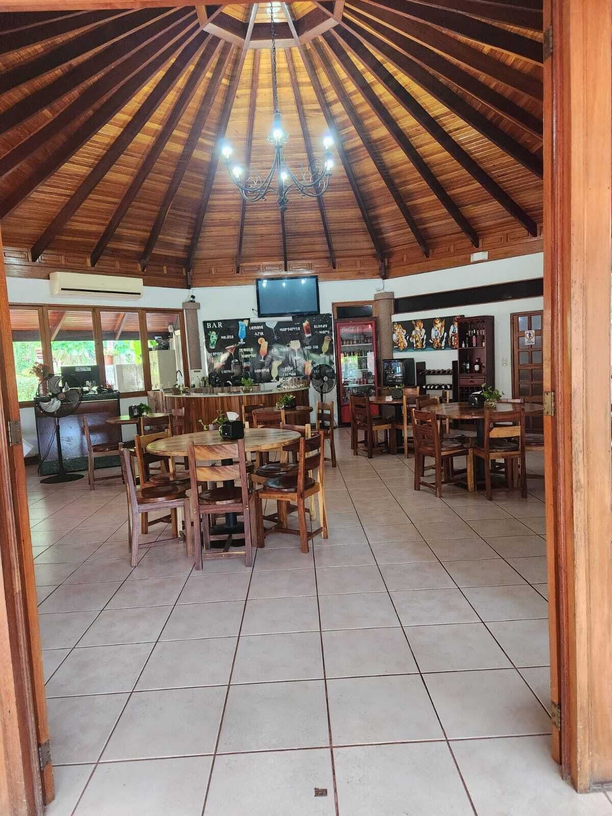 Un restaurante con techo de madera, piso de baldosas y varias mesas y sillas.
