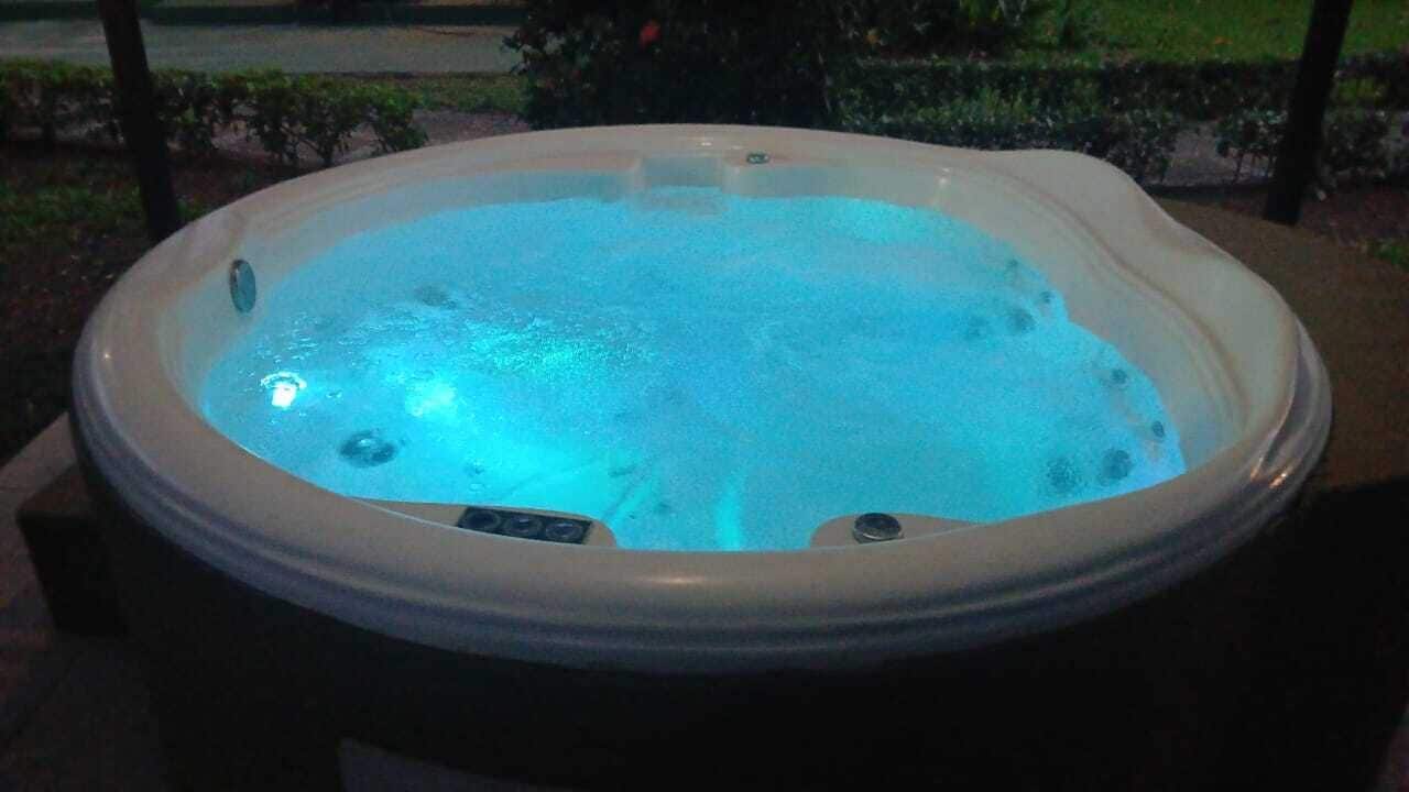 Een bubbelbad met blauw licht, omringd door een donker terras.